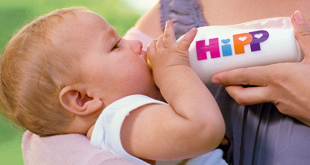 Kūdikis geria iš buteliuko su užrašu "HiPP".